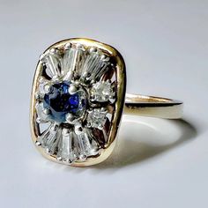 a gold ring with a blue and white diamond in the center on a white surface