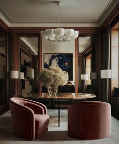 a living room with two chairs and a table in front of a painting on the wall