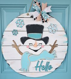 a wooden snowman ornament hanging on a blue door with the word hello