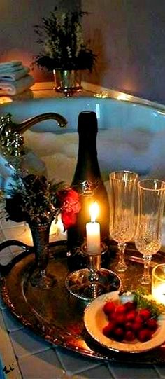 a tray with wine glasses, strawberries and candles on it in front of a jacuzzi tub