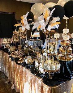 a table topped with lots of desserts and balloons in the shape of black, white and gold