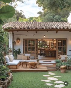 an outdoor living area with wooden furniture and plants on the lawn, surrounded by greenery