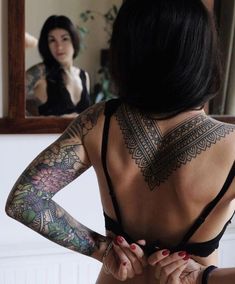 a woman with tattoos standing in front of a mirror