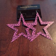 pink and black leopard print star shaped earrings on a wooden table next to a pair of scissors