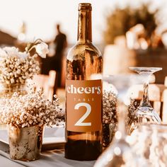 a bottle of wine sitting on top of a table next to vases filled with flowers