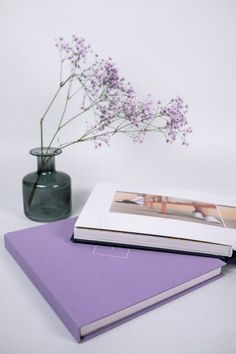 a purple book and vase with flowers in it