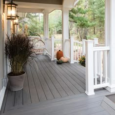 the front porch is decorated with white pillars and wood flooring, along with a potted plant