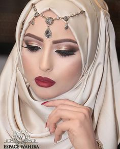 a woman wearing a white hijab with jewels on her head and red lips