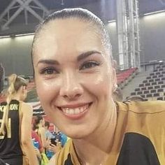 a woman is smiling for the camera in front of an audience at a basketball game