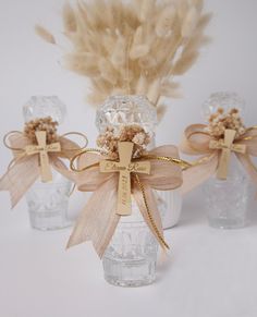 three glass vases with bows and feathers in them