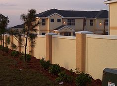 a row of houses next to a fence with trees in the foreground and a mailbox on the other side