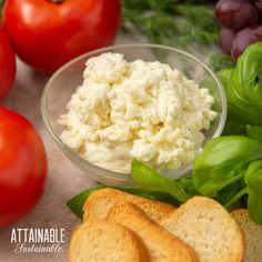 there is a bowl of cheese and bread next to tomatoes, lettuce, and grapes