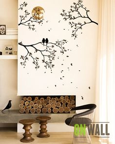 two birds sitting on a tree branch in front of a white wall with black and gold accents