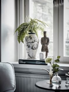 a vase sitting on top of a table next to a window