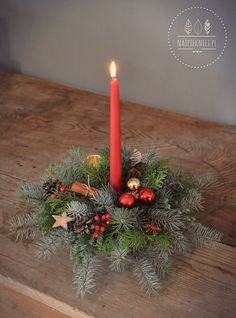 a candle is lit on top of a wreath with pine cones, berries and other decorations