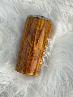 a wooden tumbler sitting on top of a white fur covered floor next to a metal lid