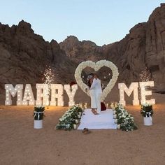 a newly married couple standing in front of a large sign with the word marry me written on it