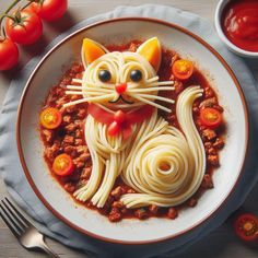 a white plate topped with pasta and a cat face on top of it next to tomatoes