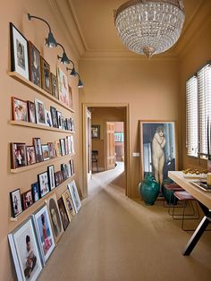 a long hallway with pictures on the wall and a chandelier hanging from the ceiling