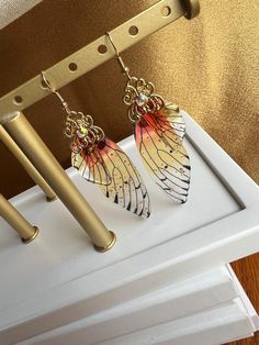 three pairs of earrings hanging from hooks on a door handle in front of a gold wall