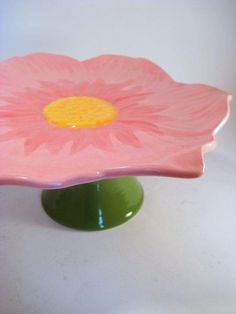 a pink flower sitting on top of a green vase