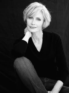 a black and white photo of a woman sitting on the ground with her hand under her chin