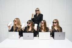 four women sitting at a table with laptops and coffee cups in front of them