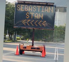 a sign that is on the side of the road with traffic cones in front of it