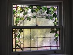 a stained glass window with green leaves on the outside, and white trim around it