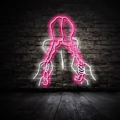 a pink neon sign on the side of a brick wall that has a woman's legs crossed