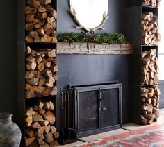 a fireplace with logs stacked on top of it and a mirror above the fire place