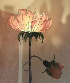 a flower that is sitting on top of a lamp shade with the light shining on it