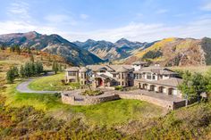 this is an aerial view of a large home in the mountains with trees and grass