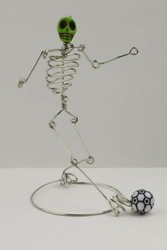 a metal skeleton with a soccer ball on it's feet is shown in front of a white background