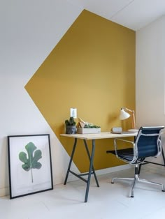 an office with a desk and chair in front of a wall painted yellow, white and grey