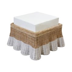 a wicker ottoman with white cushions and brown stripes on the bottom, in front of a white background