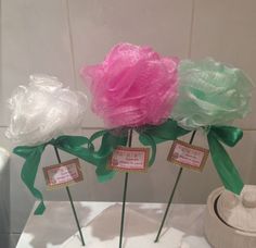 three pink and green flowers on top of a white table cloth with tags attached to them