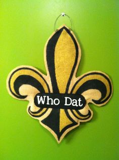 a sign that says who dat on the side of a green wall with a black and yellow fleur de l'oeuvret