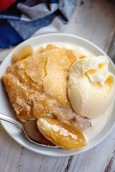 a white plate topped with fruit and ice cream on top of a wooden table next to a spoon