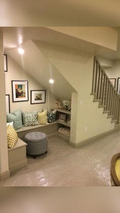 a living room filled with lots of furniture and pictures on the wall next to stairs