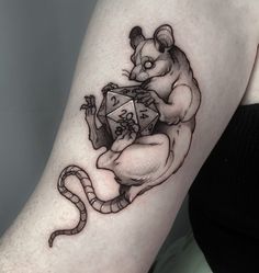 a woman's arm with a tattoo of a rat holding a dice on it