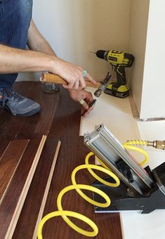 a man is working on wood flooring with power tools and screwdrivers in the background