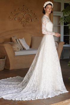 a woman in a white wedding dress standing on a stone floor next to a couch