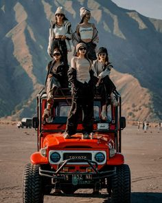 a group of people riding on the back of an orange jeep