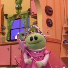 the frog is dressed in pink and holding a wand