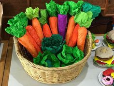 a basket filled with carrots and lettuce on top of a white table