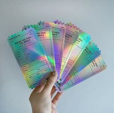 a person holding five tickets in their left hand and the other one has a rainbow sticker on it