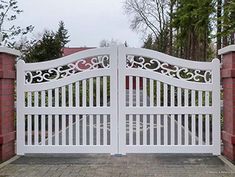 a white gate with an intricate design on the top and bottom, in front of a brick wall