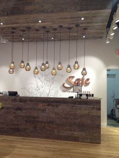 a reception area with lights hanging from the ceiling and wood flooring on the walls