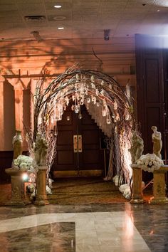 an archway decorated with flowers and candles in the middle of a lobby area at a hotel